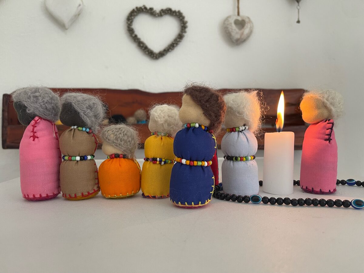 Small handmade dolls standing in for family members in a 1-on-1 Family Constellation, with a lit candle beside them